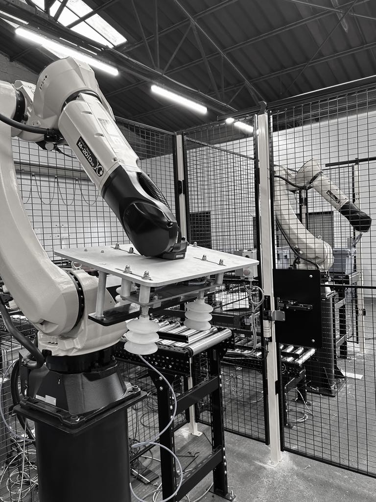 Robots Fanuc pour le prélèvement de bacs dans un environnement logistique, avec des pinces robotisées à vide. L'alimentation et le déchargement sont assurés par des convoyeurs à rouleaux, des convoyeurs à chaîne, des convoyeurs à bande, des systèmes de tri et des convoyeurs à rouleaux par gravité.